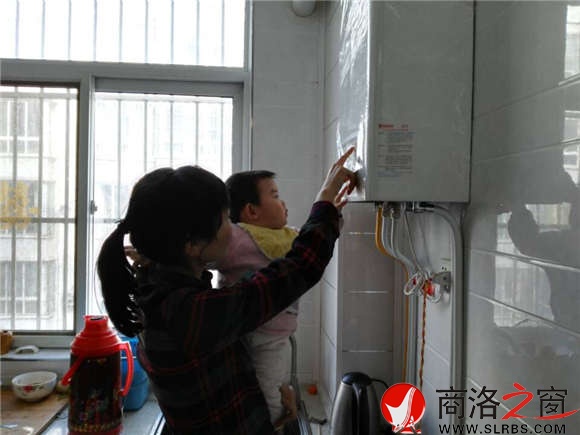 家住市區(qū)香菊小區(qū)的李女士正在操作自家剛剛安裝的燃氣壁掛爐，提升室內(nèi)的溫度。