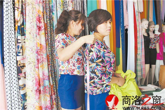 雷小莉仔細(xì)地為客人量尺寸，量體裁衣是裁縫鋪?zhàn)畲蟮膬?yōu)勢(shì)。